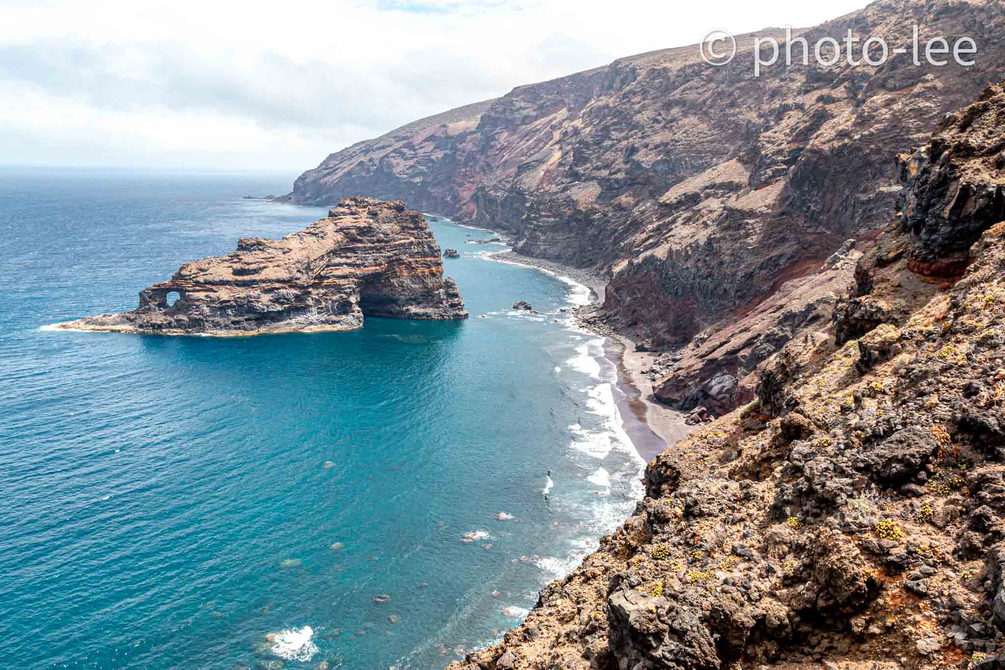 Eine kleine Gesteinsinsel steht im türkiesem Wasser vor der Küste La Palmas